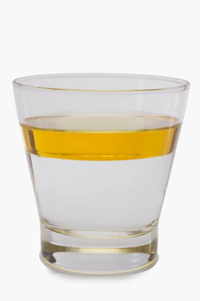 A glass showing olive oil floating above water: oil at the top, water below, separated by their nature.
