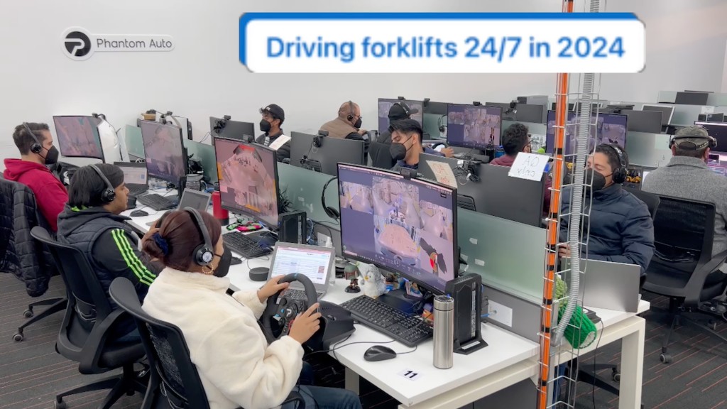 Phantom Auto remote operators at their stations driving forklifts remotely with steering wheels and screens
